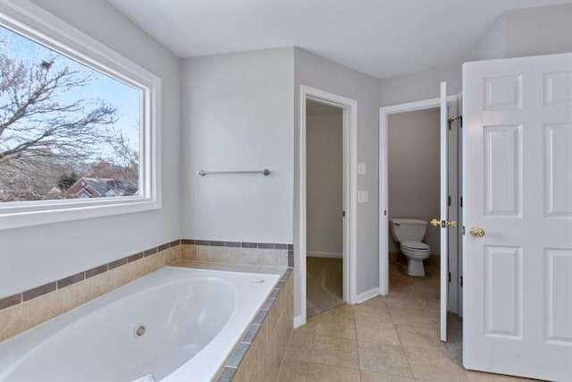 bathroom with tile patterned flooring, a relaxing tiled tub, and toilet