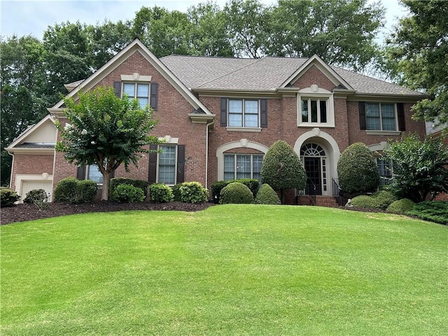 view of front facade with brick siding and a front lawn