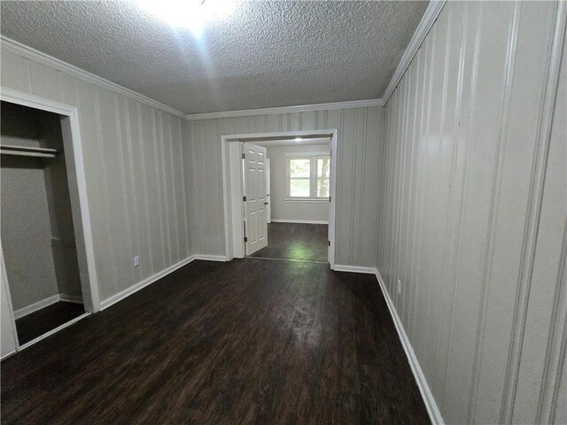 spare room with a textured ceiling, crown molding, and dark hardwood / wood-style floors