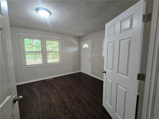 foyer entrance with a textured ceiling and dark hardwood / wood-style flooring