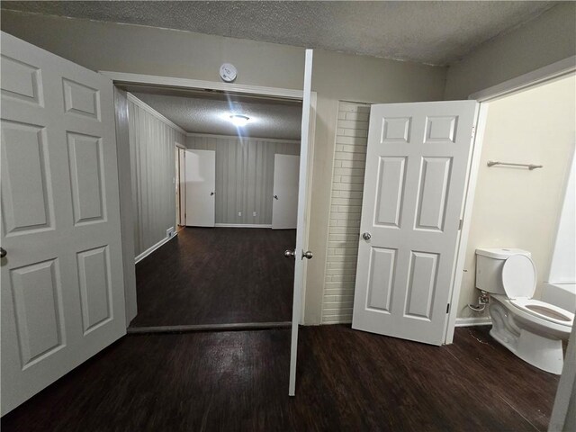 interior space featuring wood-type flooring, a textured ceiling, and toilet