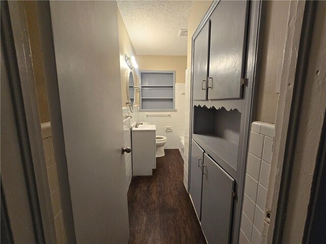 bathroom featuring hardwood / wood-style flooring, vanity, toilet, and a textured ceiling