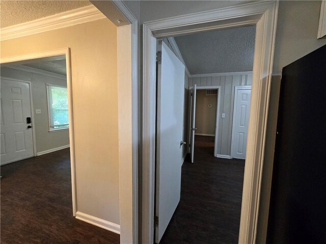 hallway with a textured ceiling, crown molding, and dark wood-type flooring