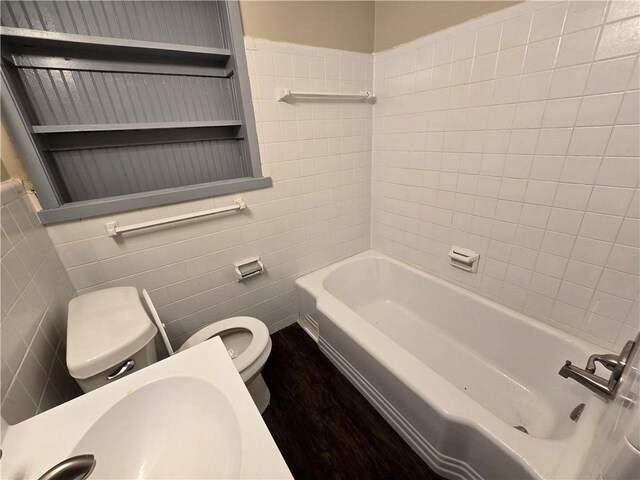 bathroom with sink, a bath, tile walls, and toilet