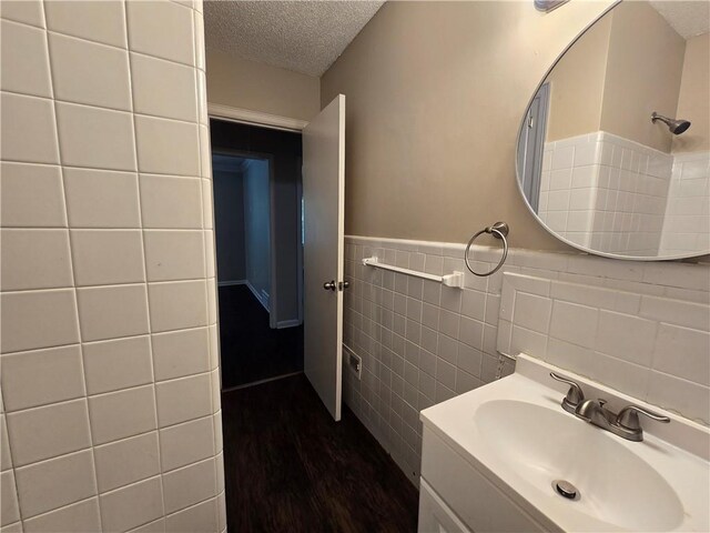 bathroom featuring a shower, a textured ceiling, vanity, tile walls, and hardwood / wood-style flooring