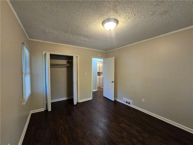 unfurnished bedroom featuring a textured ceiling, crown molding, dark wood-type flooring, and a closet