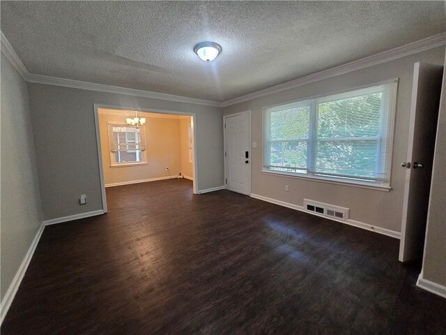 spare room featuring dark wood-type flooring, ornamental molding, a textured ceiling, and a notable chandelier