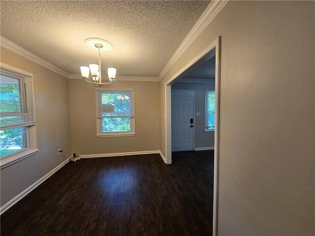 unfurnished dining area with a textured ceiling, dark hardwood / wood-style floors, an inviting chandelier, and crown molding