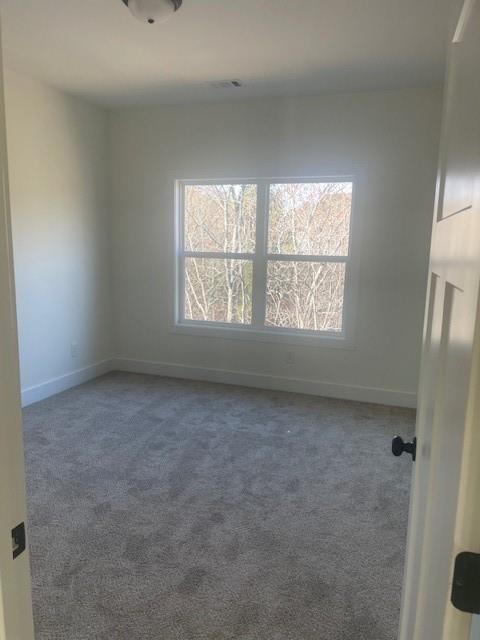 carpeted empty room featuring plenty of natural light and baseboards