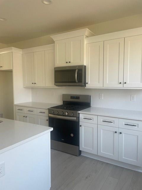 kitchen with white cabinets, stainless steel appliances, and light countertops