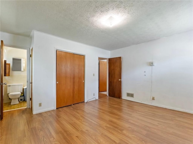 784 San Miguel Dr, Stone Mountain, GA 30083 - unfurnished bedroom with light wood-type flooring, a textured ceiling, a closet, and ensuite bathroom