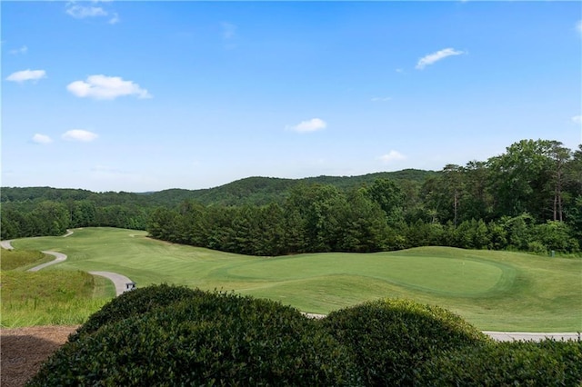 view of home's community featuring view of golf course and a wooded view