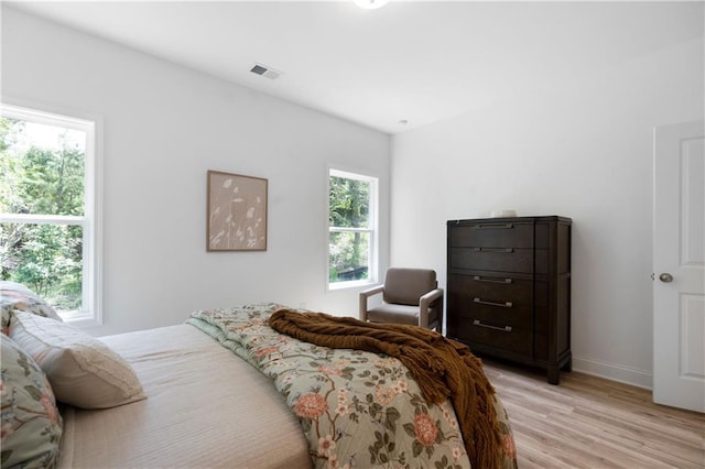 bedroom featuring light wood-type flooring, visible vents, and baseboards