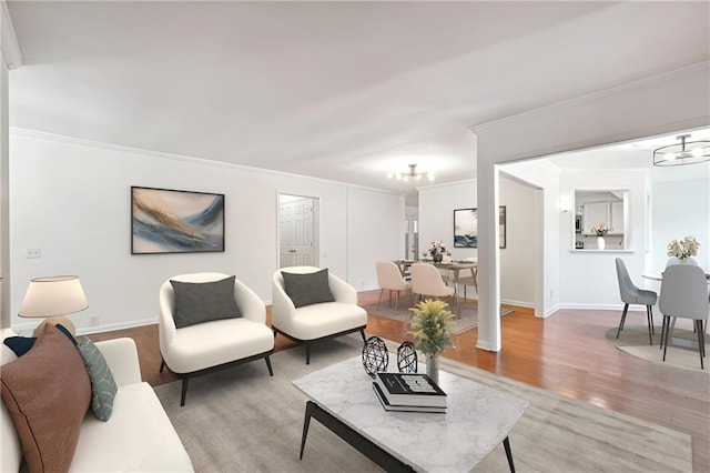 living area with crown molding, light wood-type flooring, baseboards, and a notable chandelier