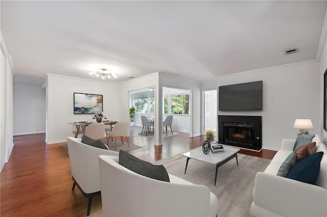 living room featuring crown molding, a fireplace, baseboards, and wood finished floors