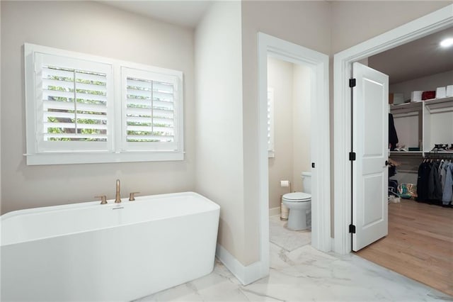 920 Wemberley Ln, Marietta, GA 30064 - bathroom with a freestanding bath, marble finish floors, toilet, baseboards, and a walk in closet