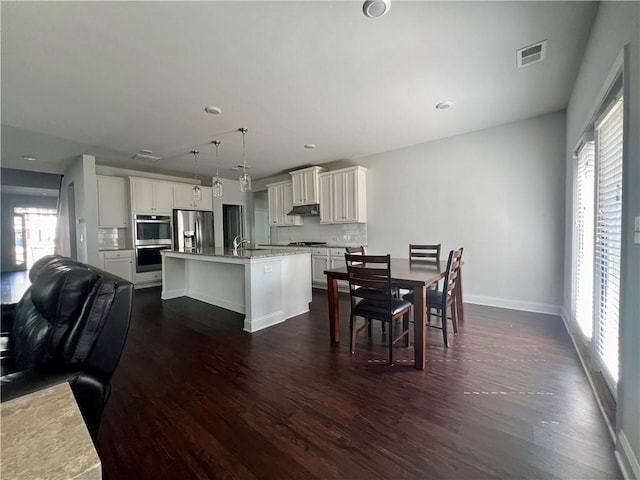 dining area featuring sink, dark wood-type flooring, and plenty of natural light