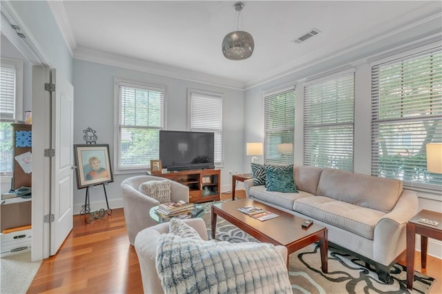 living room featuring visible vents, baseboards, ornamental molding, and light wood-style flooring