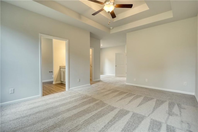 carpeted spare room with ceiling fan and a raised ceiling