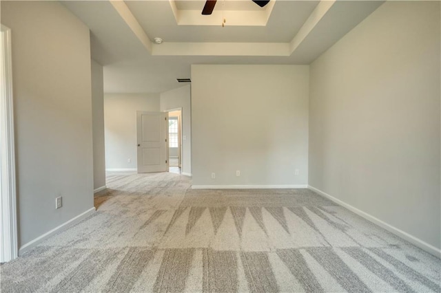 carpeted spare room featuring ceiling fan and a raised ceiling