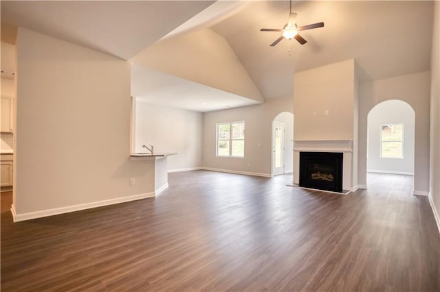 unfurnished living room featuring dark wood-type flooring, ceiling fan, and lofted ceiling