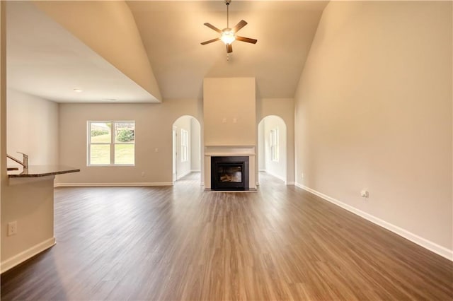 unfurnished living room with a high ceiling, dark hardwood / wood-style floors, and ceiling fan