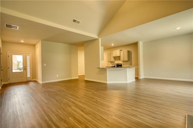 unfurnished living room with wood-type flooring and vaulted ceiling