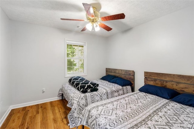 bedroom with a textured ceiling, ceiling fan, and light hardwood / wood-style floors