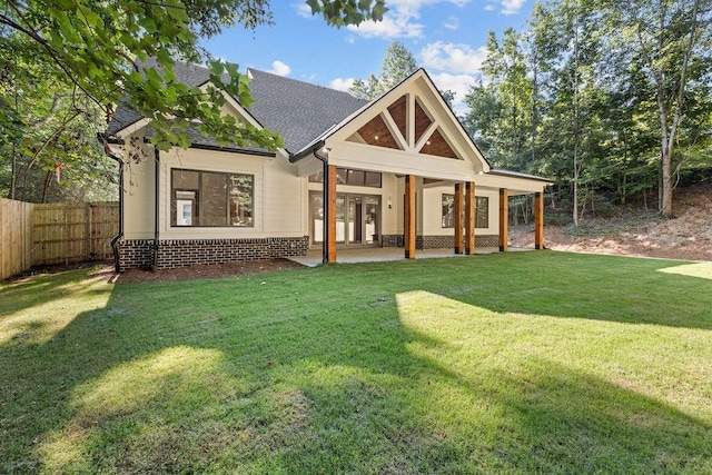back of property featuring roof with shingles, fence, and a yard