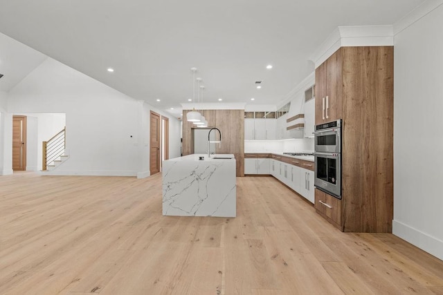 kitchen featuring a center island with sink, a sink, light wood-style flooring, and gas stovetop