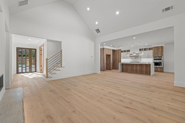 unfurnished living room featuring high vaulted ceiling, visible vents, and light wood-style floors