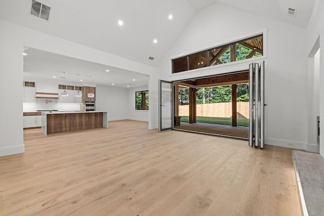 unfurnished living room featuring recessed lighting, high vaulted ceiling, visible vents, and light wood finished floors