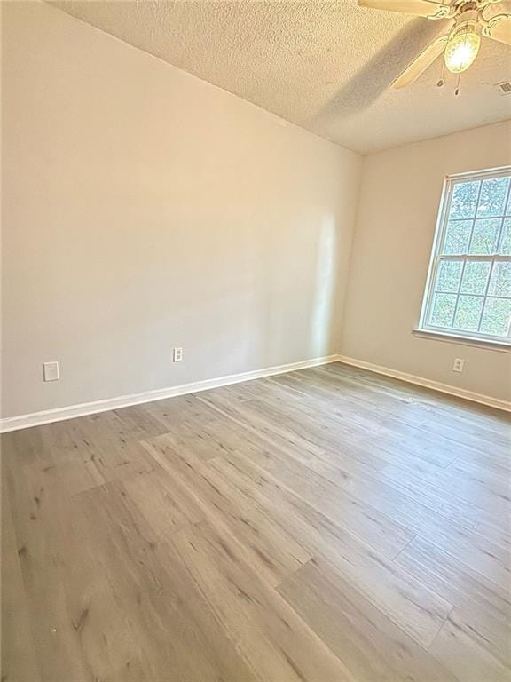 spare room featuring hardwood / wood-style flooring, ceiling fan, and a textured ceiling