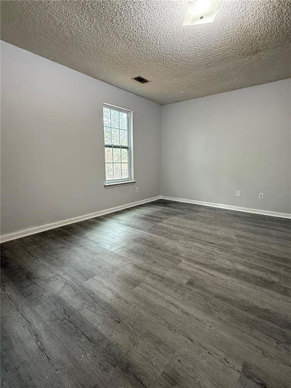 spare room featuring a textured ceiling and dark hardwood / wood-style floors