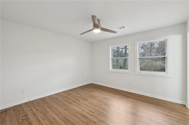 empty room with visible vents, light wood-style flooring, and baseboards