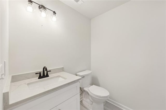 half bath featuring vanity, toilet, and baseboards