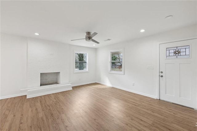 unfurnished living room with a fireplace, wood finished floors, visible vents, and baseboards