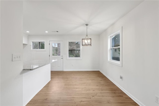 unfurnished dining area featuring recessed lighting, light wood-type flooring, visible vents, and baseboards