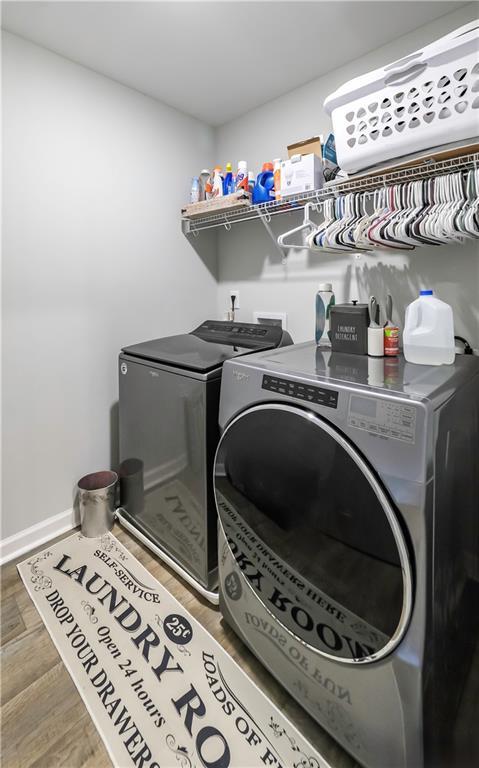 laundry room with washing machine and clothes dryer and hardwood / wood-style floors