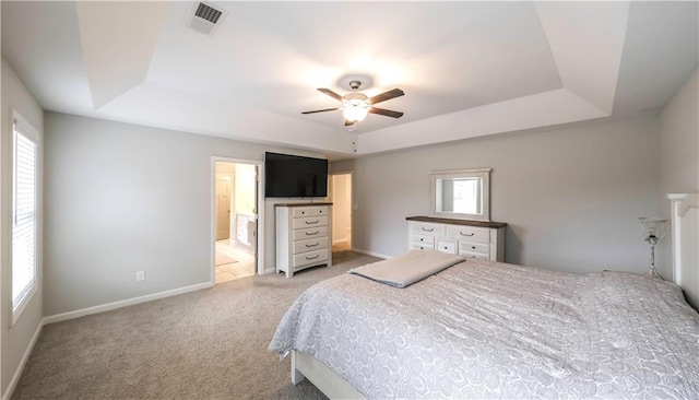 carpeted bedroom with a tray ceiling, multiple windows, and ceiling fan