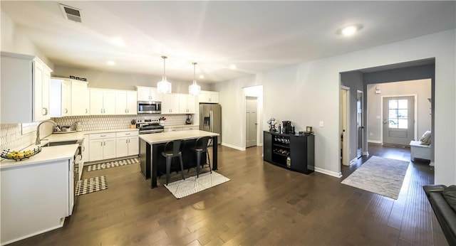 kitchen with pendant lighting, white cabinets, sink, a kitchen island, and stainless steel appliances