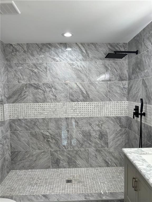 bathroom featuring tiled shower and vanity