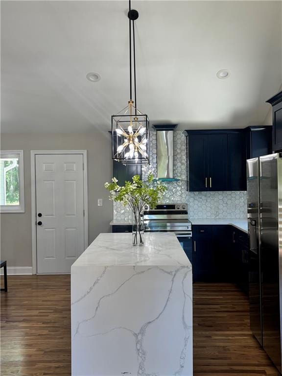 kitchen featuring wall chimney range hood, dark hardwood / wood-style floors, tasteful backsplash, a kitchen island with sink, and appliances with stainless steel finishes