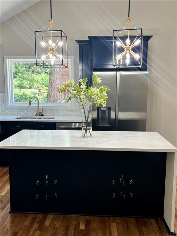 kitchen featuring a center island, a notable chandelier, a sink, and stainless steel fridge with ice dispenser