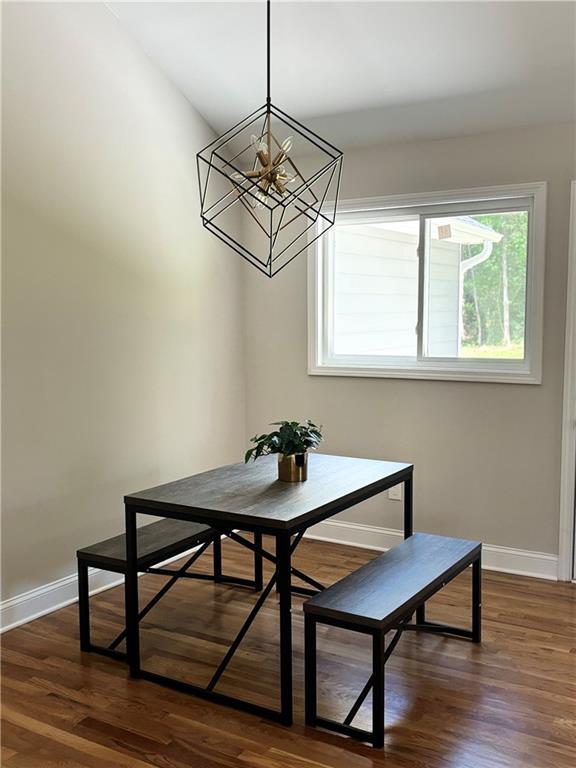 dining area with breakfast area, dark wood finished floors, baseboards, and an inviting chandelier