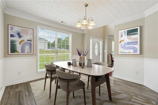 dining room featuring dark hardwood / wood-style floors, ornamental molding, a textured ceiling, and an inviting chandelier