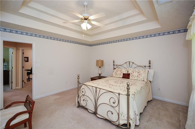 carpeted bedroom with a tray ceiling and ceiling fan