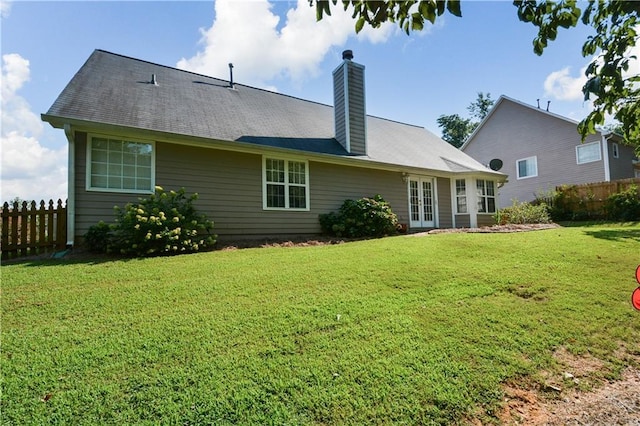 rear view of house featuring a lawn and french doors