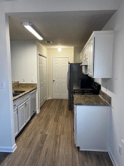 kitchen with dishwasher, white cabinets, black range oven, dark stone countertops, and dark hardwood / wood-style flooring