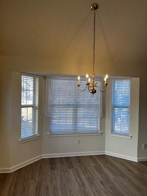 unfurnished dining area featuring dark hardwood / wood-style flooring and an inviting chandelier